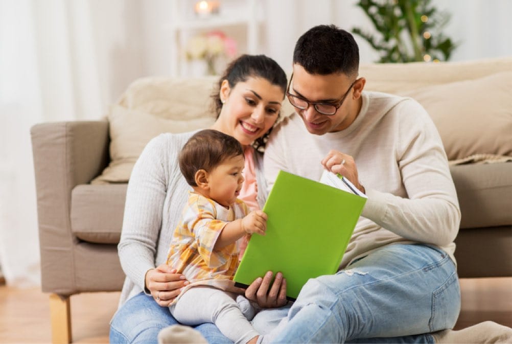Happy family with baby reading book at home