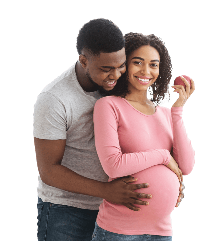 Happy pregnant african woman eating apple while her husband hugging her from behind